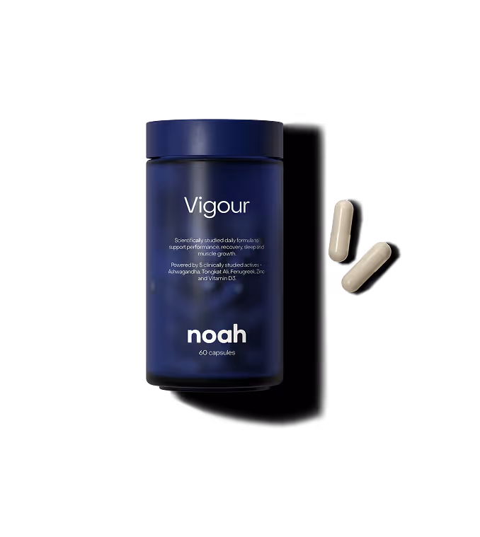 Blue bottle of Vigour dietary supplement by noah with two capsules next to it.