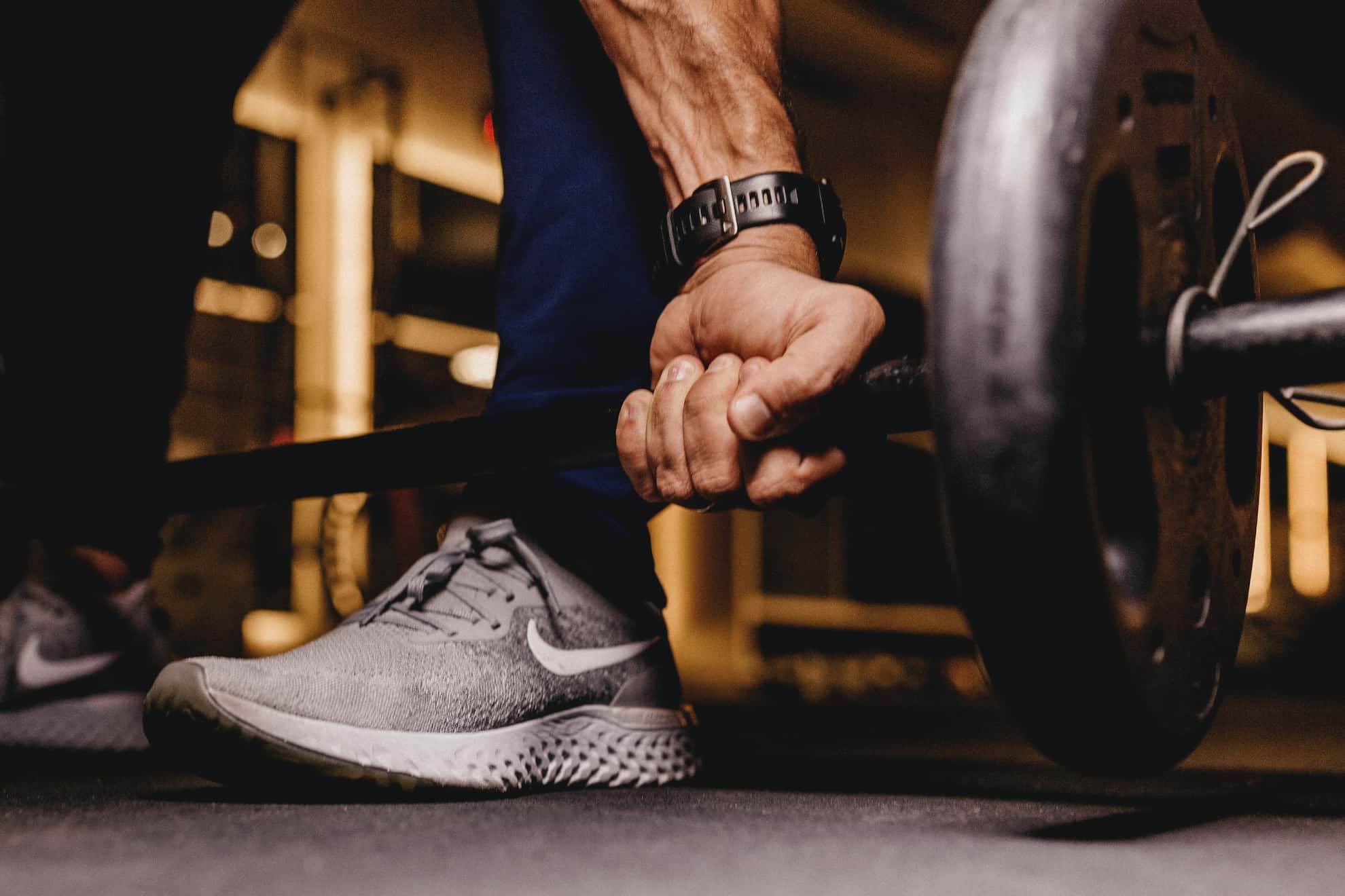 A man holding on to a long barbell lying on the ground