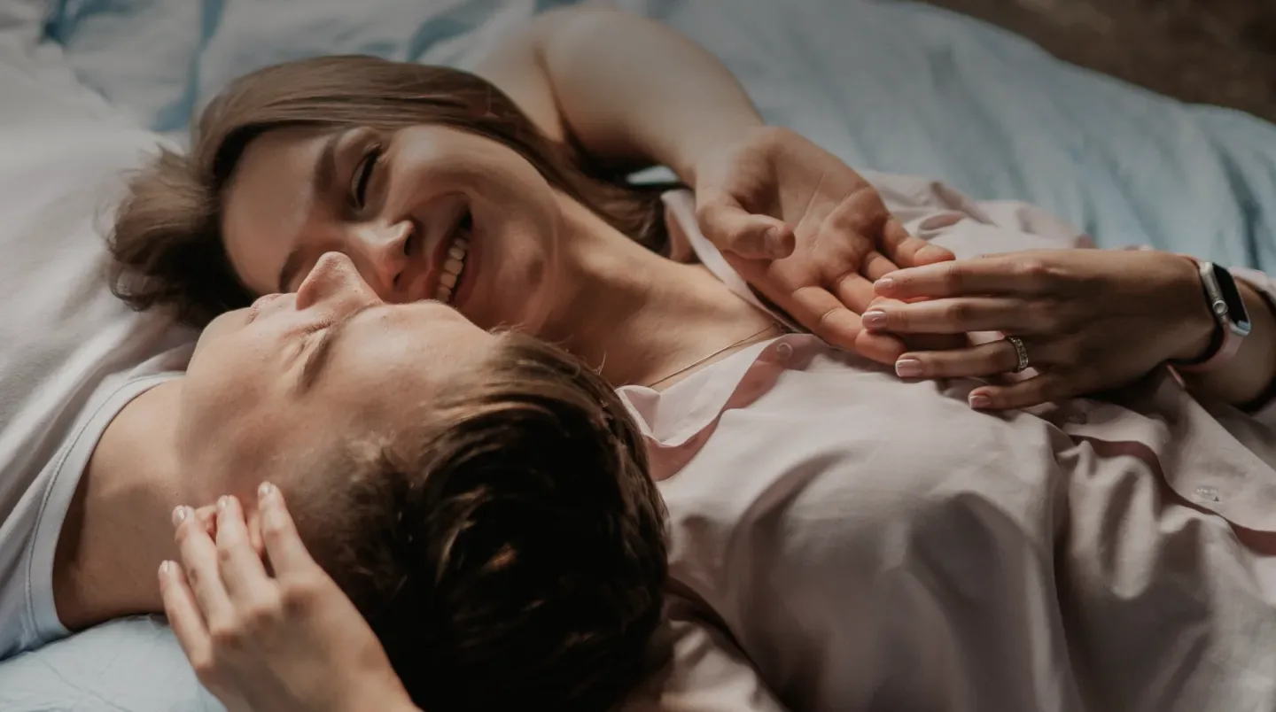 A couple lying close together in bed, smiling