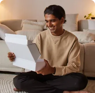 A man at home opening a plain delivery box