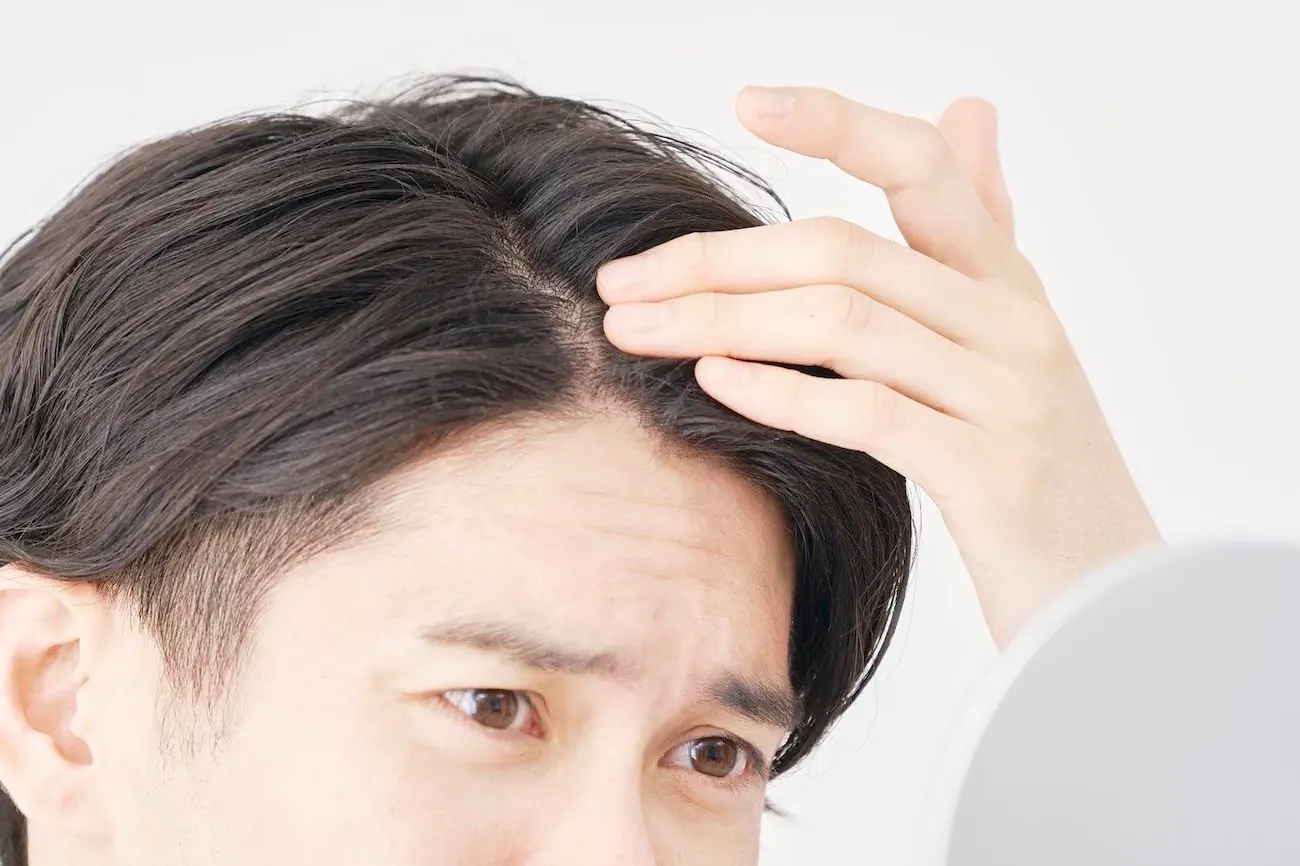 A man checking his hairline in the mirror