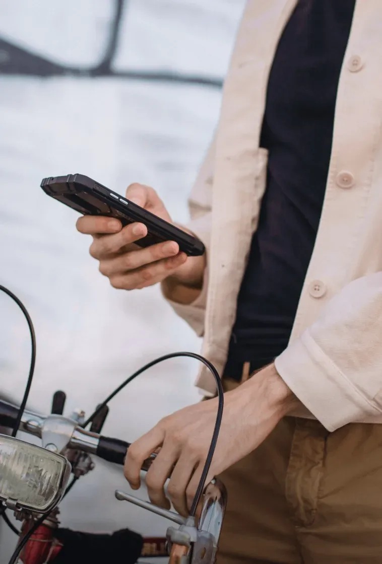A man checking his phone with his bicycle