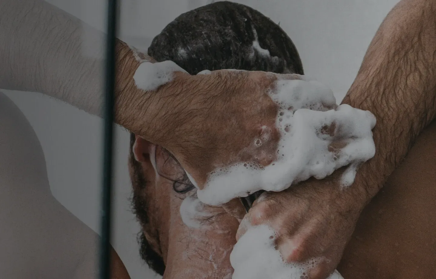 A man lathering shampoo into his hair