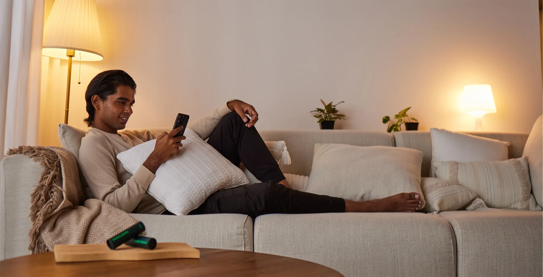 A man relaxing on his sofa in the evening, looking at his phone