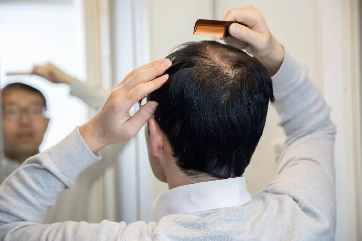 A man styling his hair in the mirror