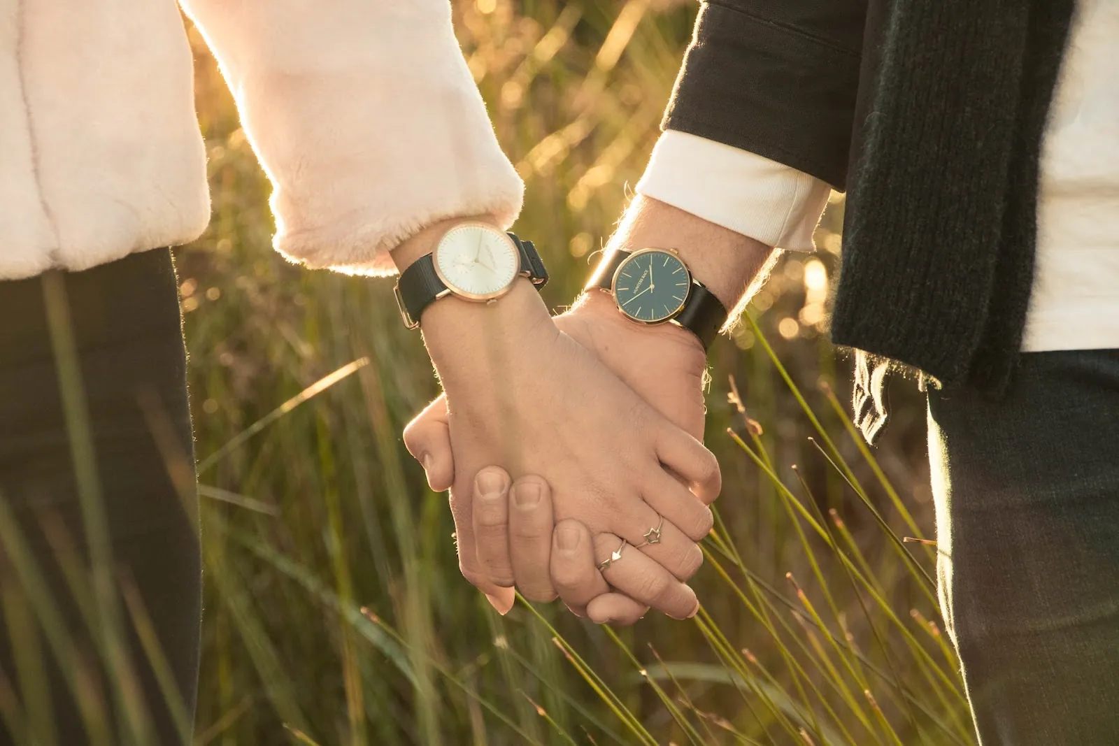 A couple (man and woman) wearing watches, holding hands together.