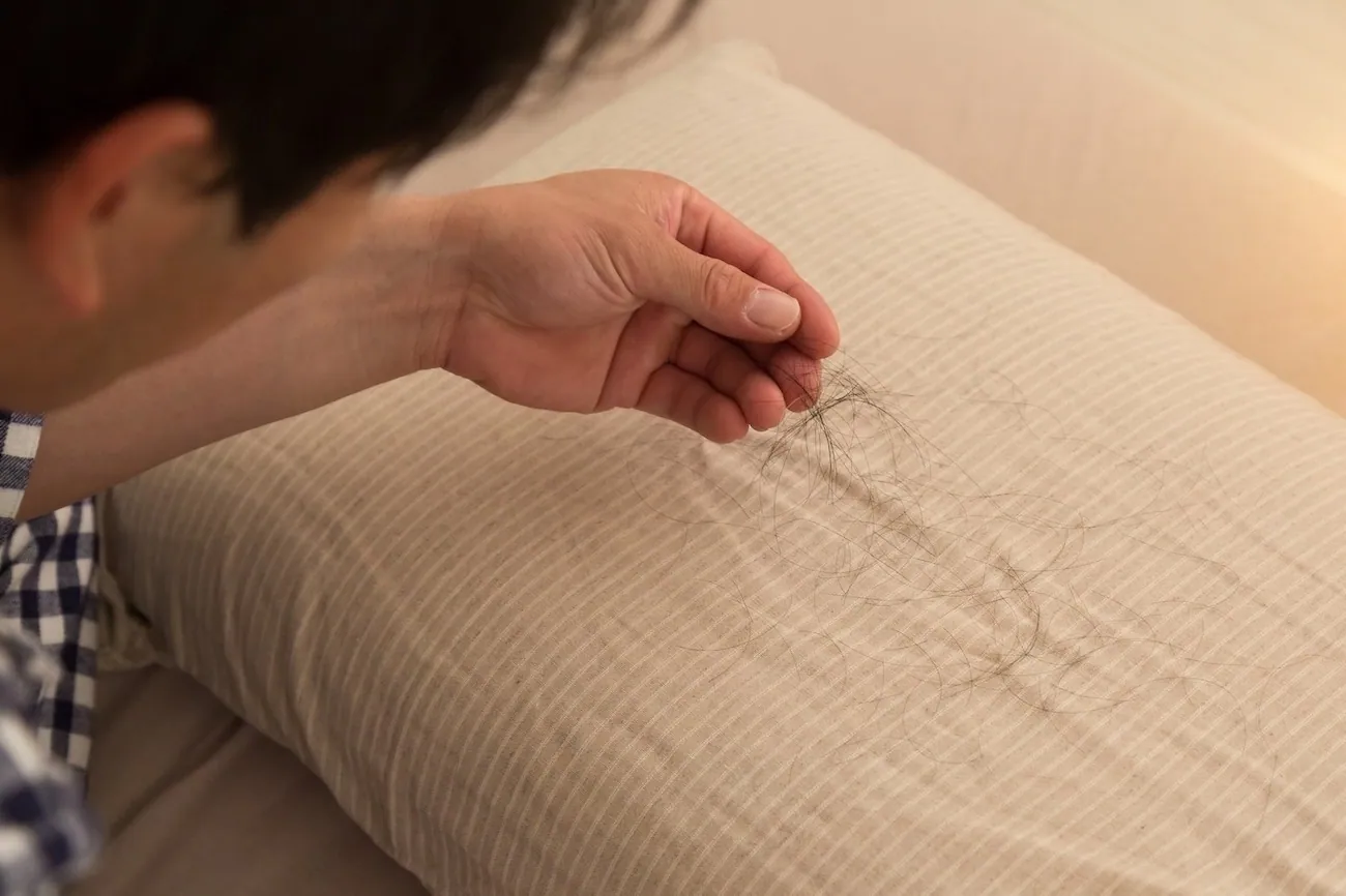 A man worried about finding fallen hair on his pillow