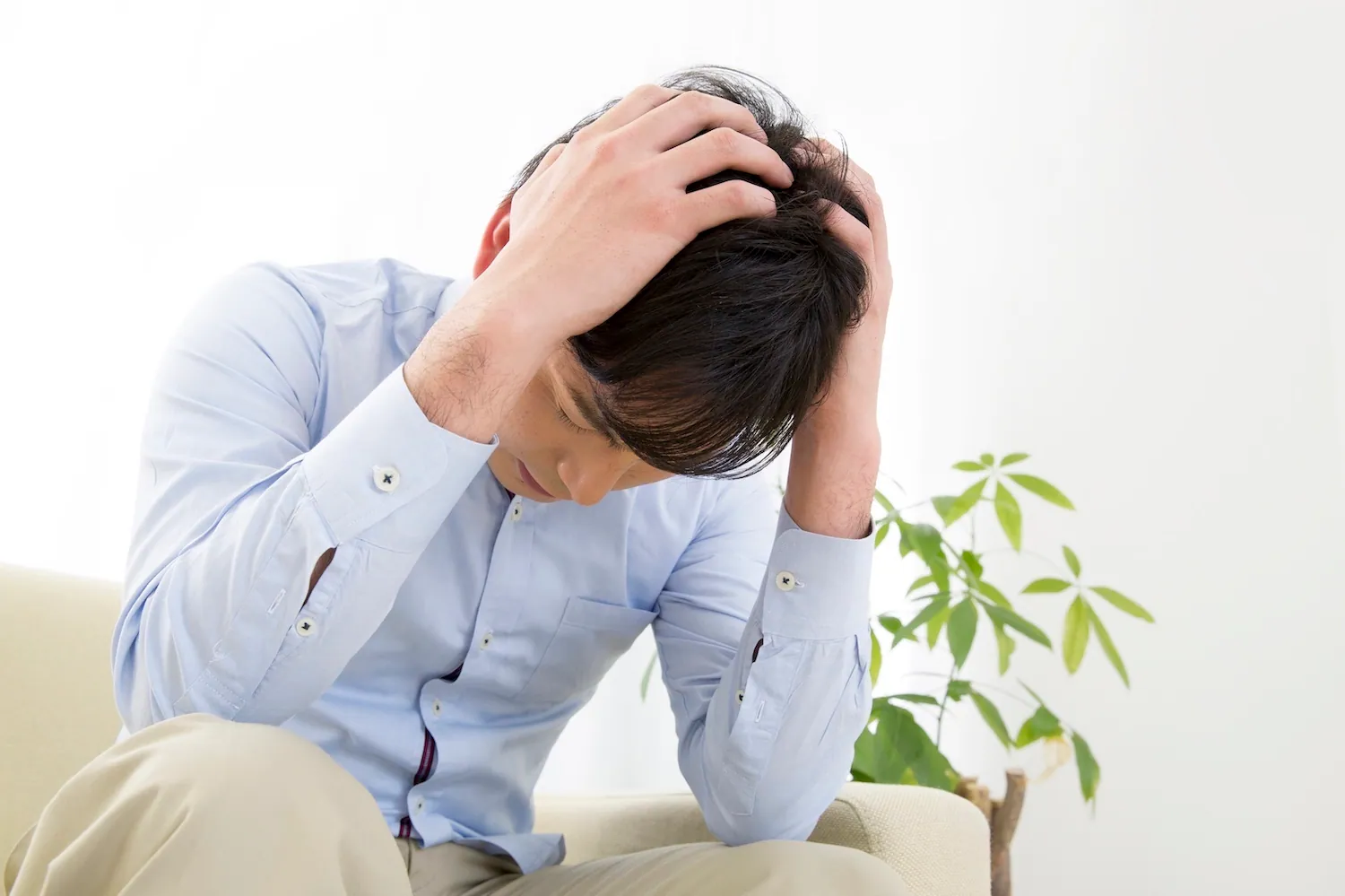 A distressed Asian male grabbing his hair with both his hands