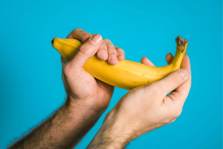 Two hands holding on to a ripe banana