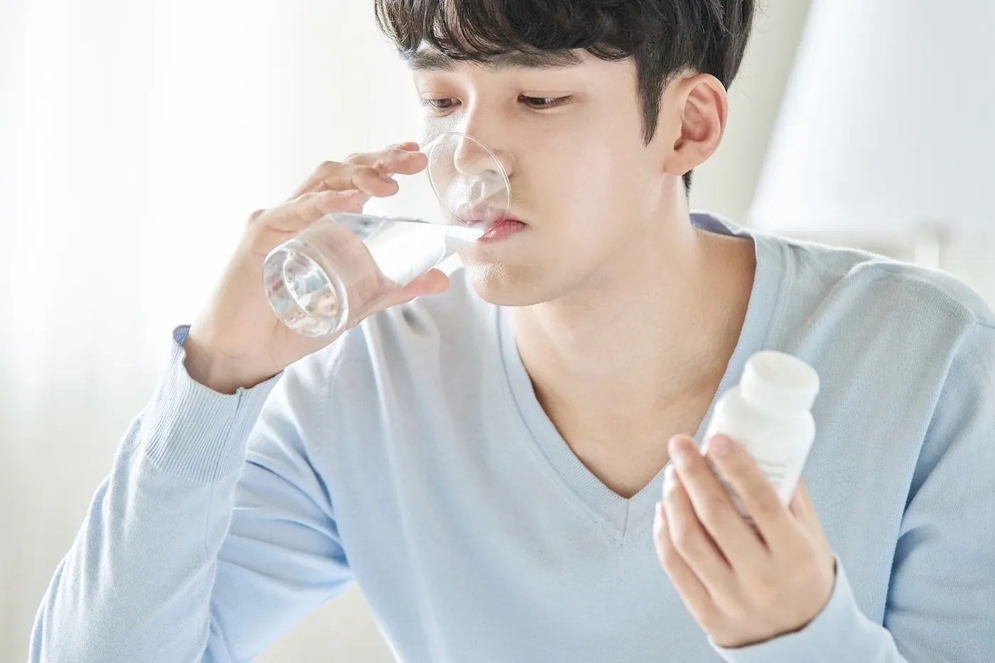A man drinking water to swallow his medicine