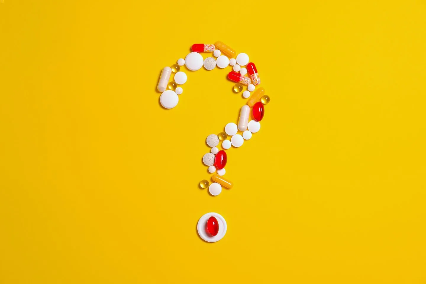 A collection of medications formed into a question mark ("?") shape against a yellow background
