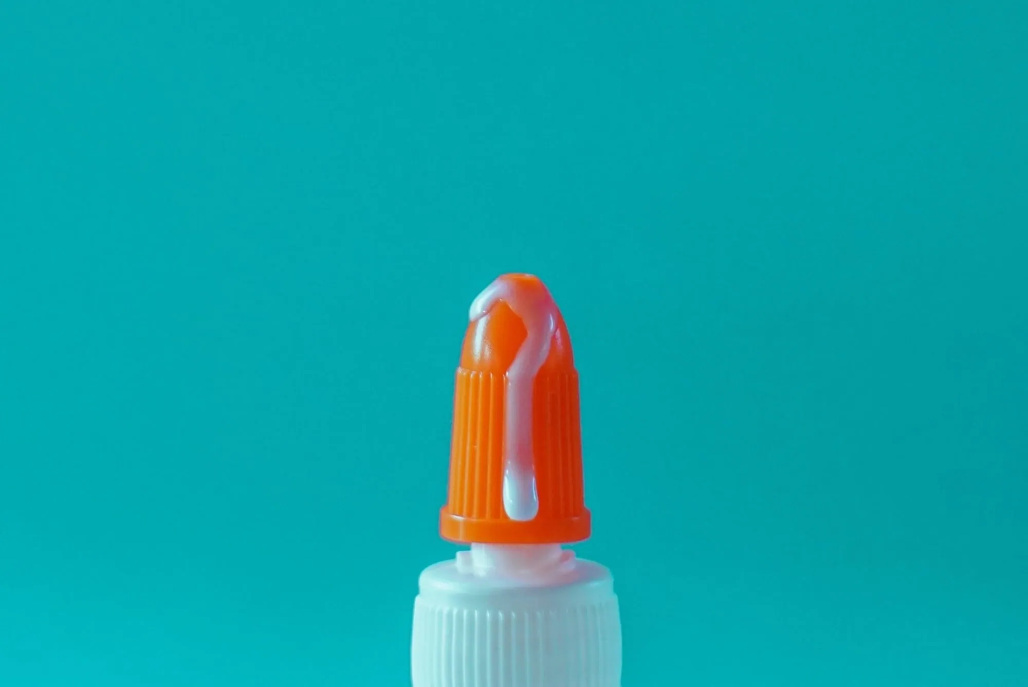 White glue overflowing from the tip of a glue container