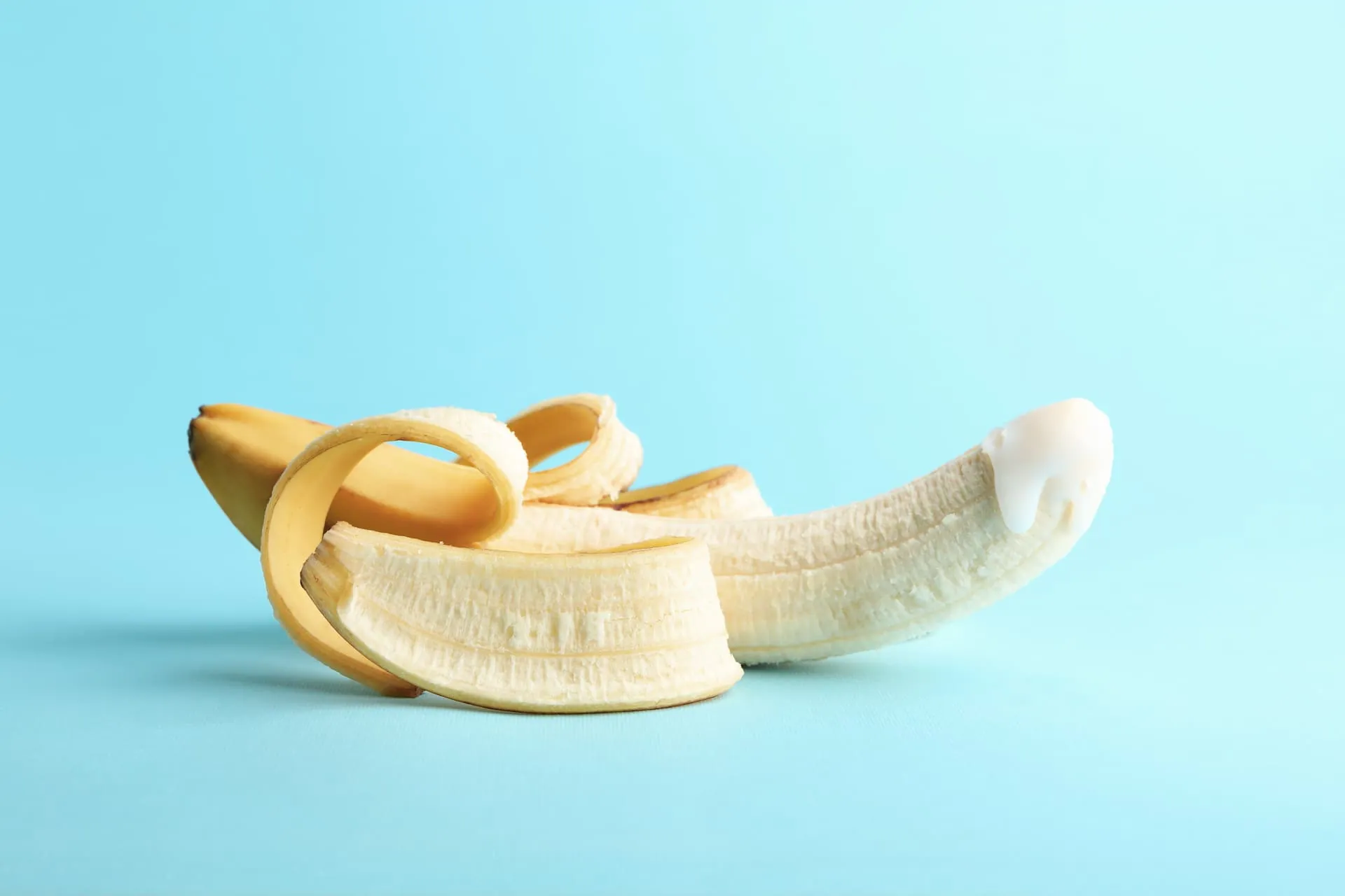 A half-peeled banana against a sky-blue background