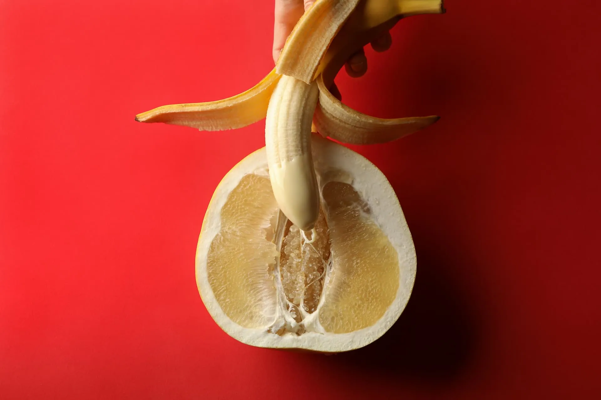 A half-peeled banana being inserted into the center of a half-cut lemon