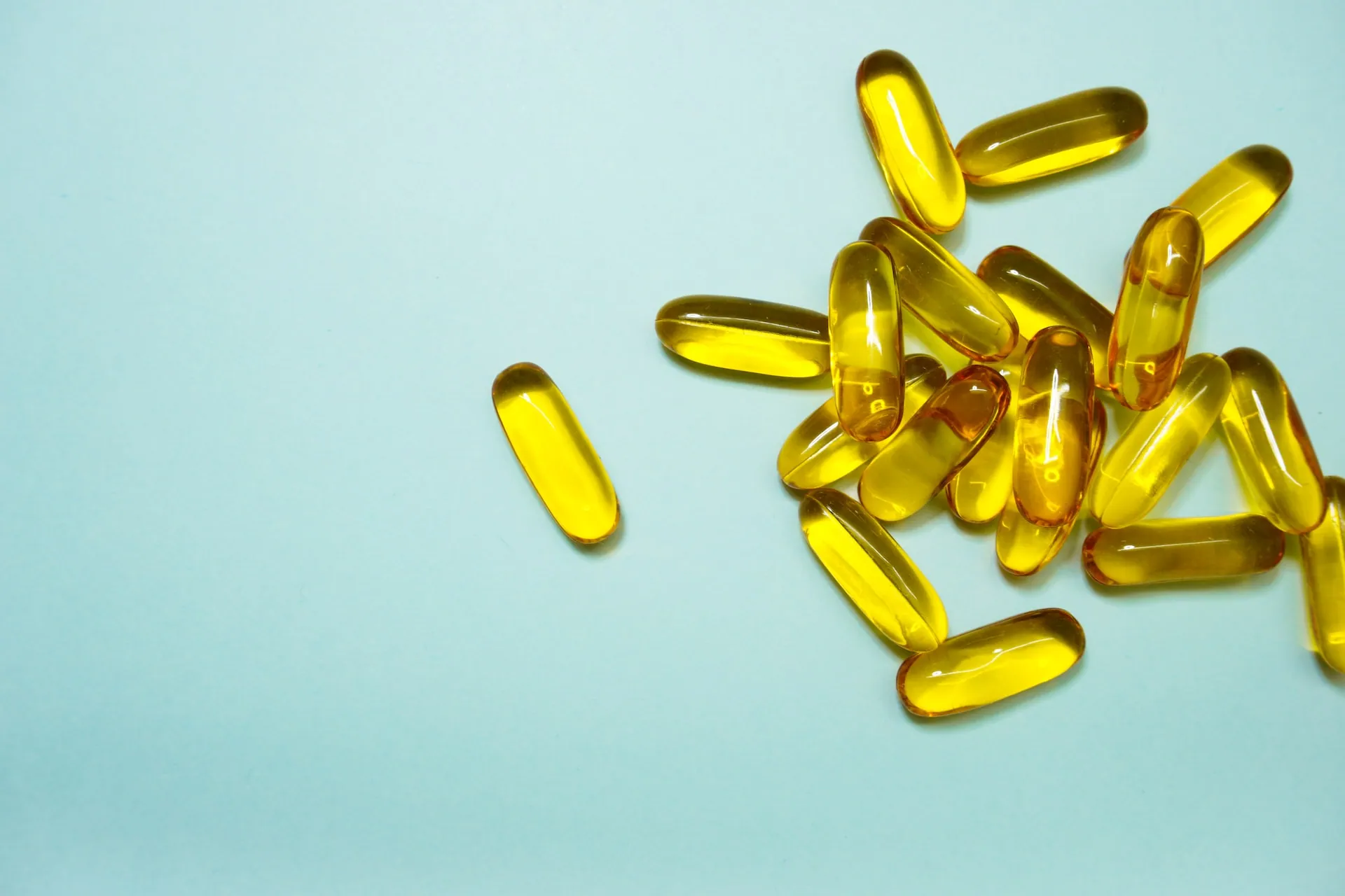 Scattered fish oil tables against a mint-green background