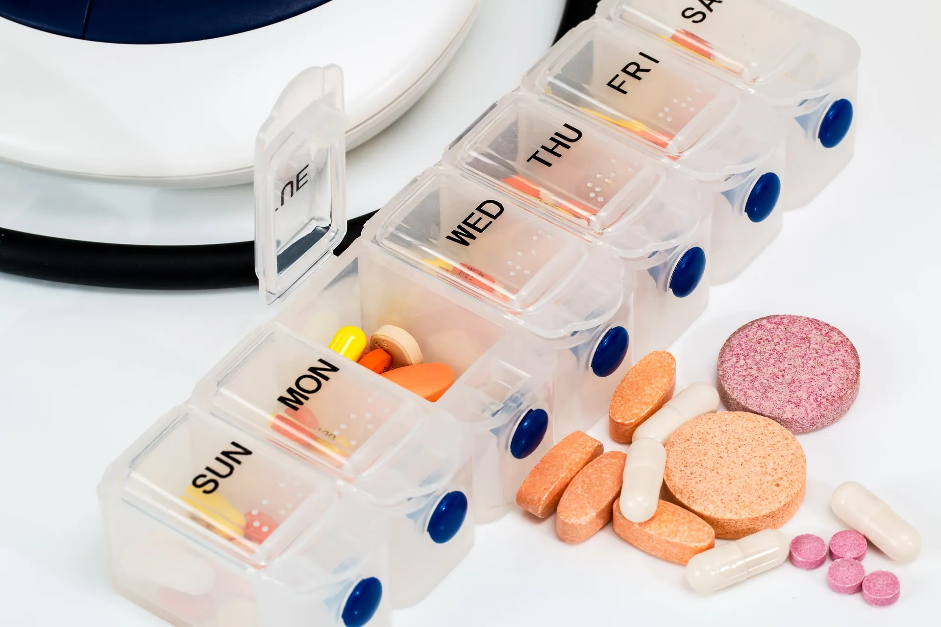 A collection of medications inside a container with compartments labeled for each day of the week