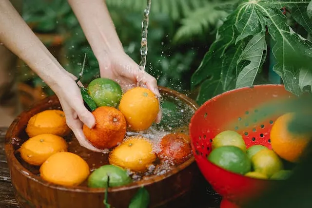 A person washing  bunch of citrus fruits