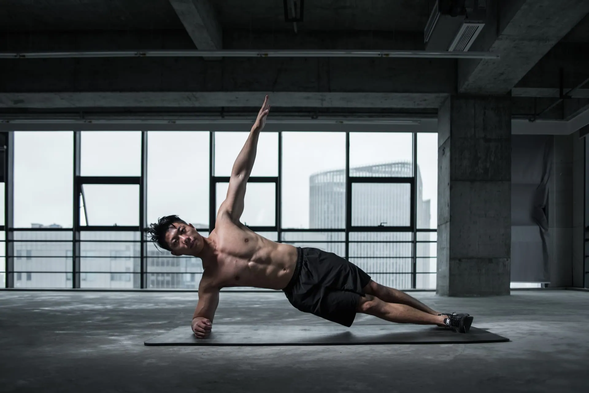 A lean and muscular Asian male doing side planks