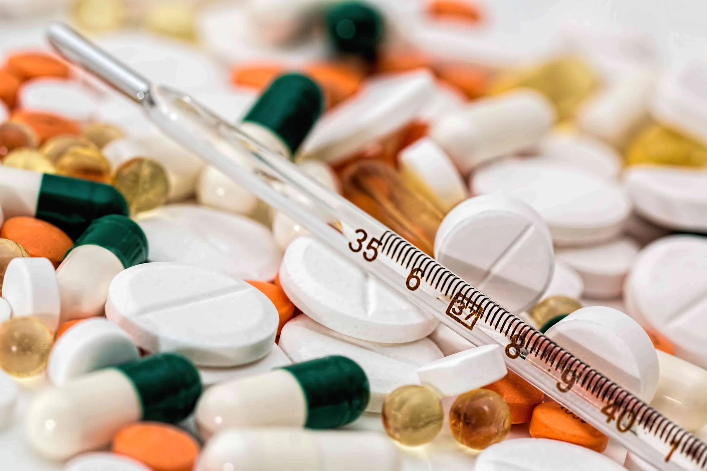 A glass thermometer in between a large collection of pills