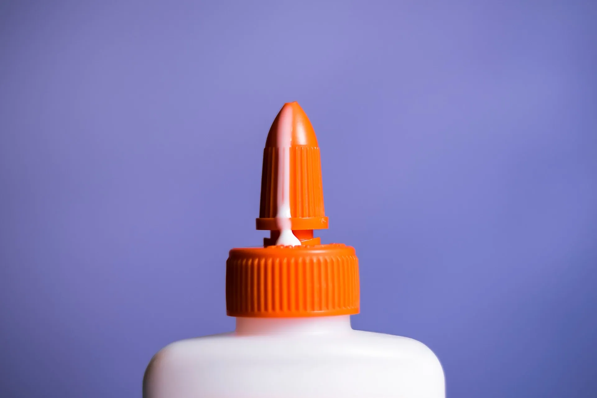 A bottle of white glue overflowing at the tip in a suggestive manner